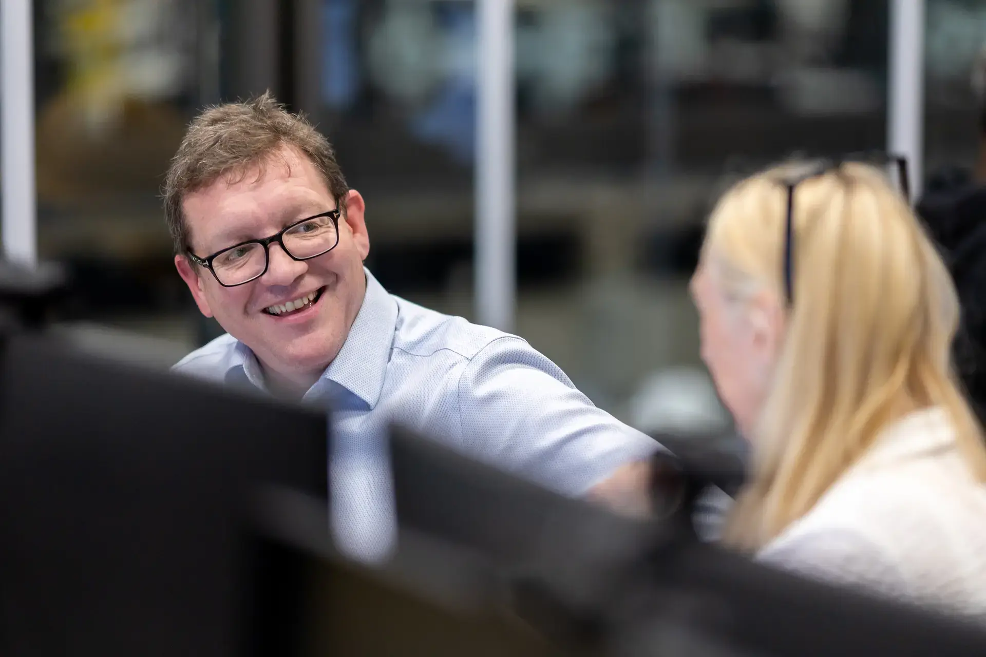 Colleagues talking infront of computers in office
