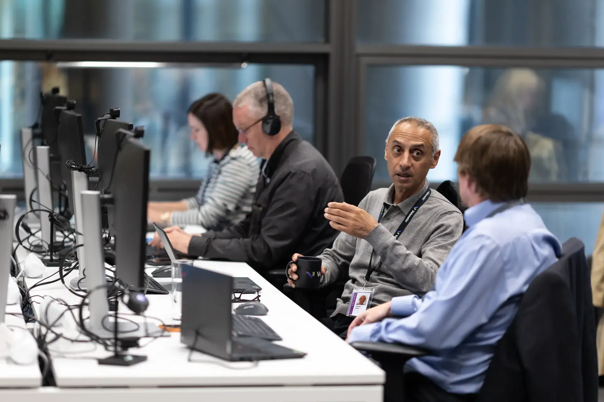 People talking and working on laptops in office